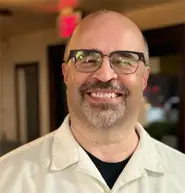 judge-advocate-michael-carl-us-navy-veteran-is-wearing-glasses-and-a-white-shirt-while-taking-a-photo-with-a-smile